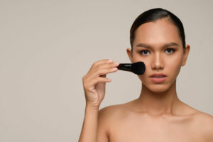 Mujer aplicándose base de maquillaje profesional